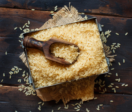 Parboiled rice in a metal box with a wooden spoon top viewの写真素材