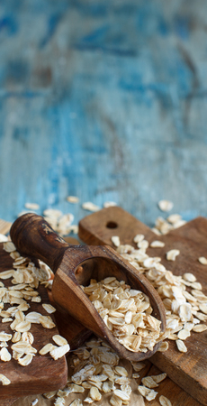 Rolled oats close up on a blue table with a wooden spoonの写真素材