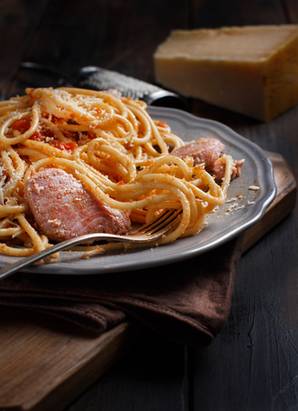 Spaghetti with chunks of fresh tuna, tomato and capers on a dark backgroundの写真素材