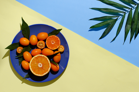 Citrus fruits on a plate on a blue and yellow backgroundの写真素材