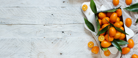Kumquat fruits in a metal box on a grey background top viewの写真素材