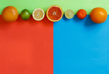 Citrus fruits on a red, green and blue background top viewの写真素材