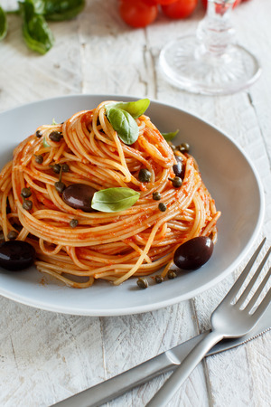 Pasta alla puttanesca - Spaghetti with tomato sauce olives and capersの写真素材