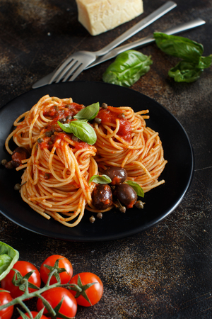 Pasta alla puttanesca - Spaghetti with tomato sauce olives and capersの写真素材