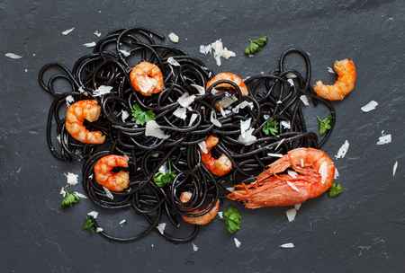 Squid ink black spaghetti with prawns and tomatoes close upの写真素材