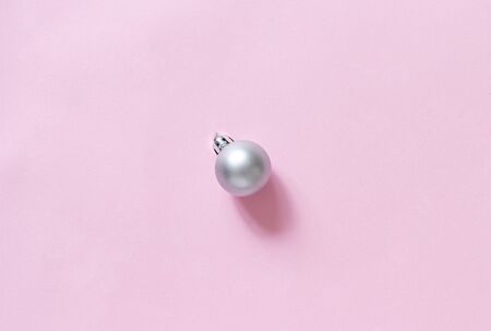Silver grey Christmas bauble on a light pink background top viewの写真素材
