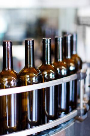 Glass bottles in bottling machine at modern wineryの写真素材