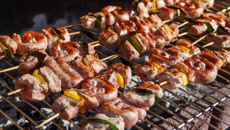 Meat and sausages skewers cooking on a grill close upの写真素材