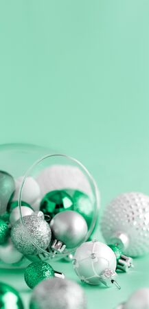 Christmas baubles in a wine glass on a light green background close upの写真素材