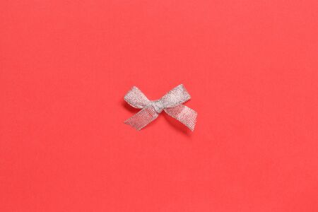 Silver Christmas bow on a coral red background top viewの写真素材