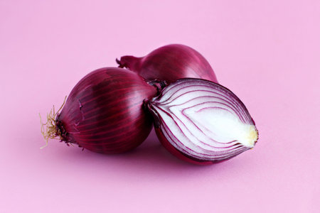 Purple onion on a light pink background close up