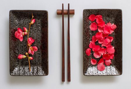 Chopsticks, rectangular plate and pink flowers on gray background. Japanese food conceptの写真素材