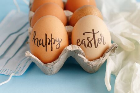 Gloves, facemask and eggs with inscription EASTER on light blue background close upの写真素材