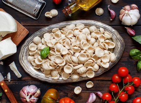 Fresh raw italian pasta orecchiette on a tray, vegetables, herbs and olive oil top view. South Italian food conceptの写真素材