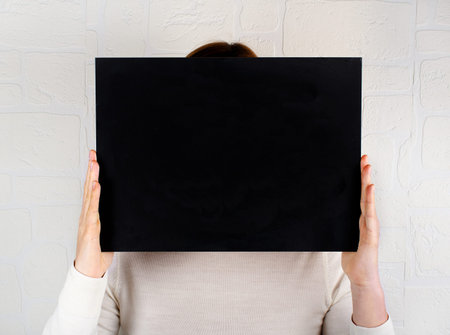 Woman keeps in hands a black empty chalkboard close up