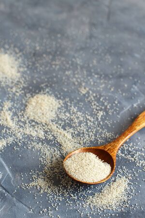 Raw uncooked fonio seeds with a spoon on grey background close up with copy spaceの写真素材