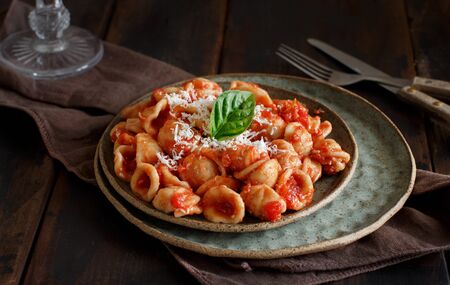 South italian  pasta orecchiette with tomato sauce and cacioricotta cheese close up on a dark table の写真素材