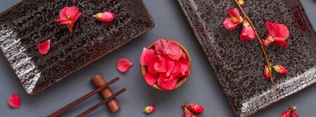 Chopsticks, rectangular plates and pink flowers on gray background. Japanese food conceptの写真素材