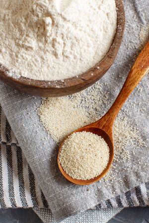 Raw fonio flour and seeds with a spoon on grey napkins close up. Alternative flourの写真素材
