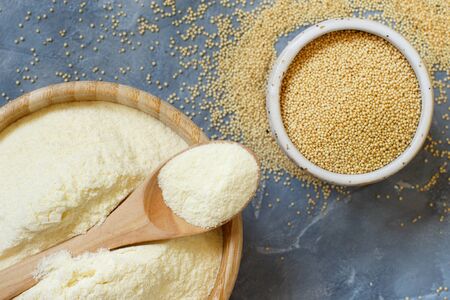 Bowl of raw Amaranth flour with a spoon and bowl of Amaranth seeds on a grey table top viewの写真素材