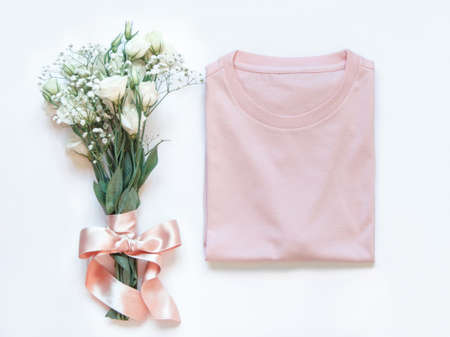 Mockup of a folded t-shirt placed near white flowers top viewの写真素材