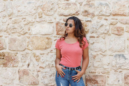 Young women wearing t-shirt and jeans stays near a wall and smileの写真素材