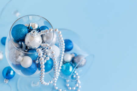 Christmas baubles in a wine glass on a light blue background close upの写真素材