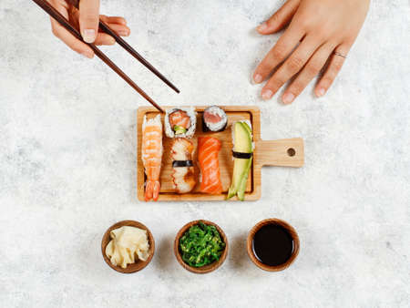 Top view of hand taking roll with chopsticks from a  plateの写真素材