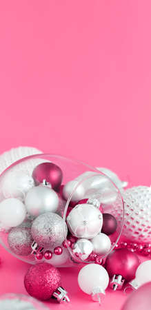 Christmas baubles in a wine glass on a pink background close upの写真素材