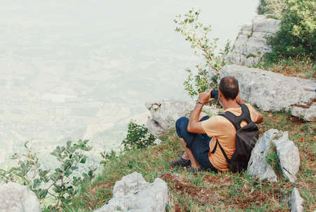 Men taking photos with mobile phone in mountains in a sunny dayの写真素材