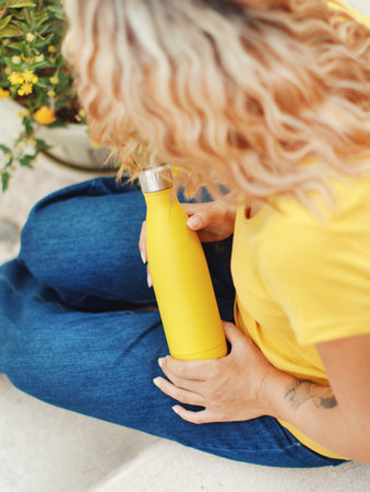 Young woman in yellow t-shirt holding yellow reusable bottle