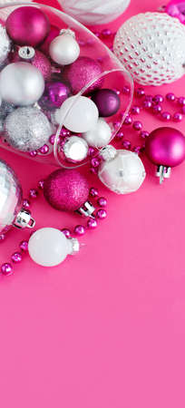 Christmas baubles in a wine glass on a pink background close upの写真素材