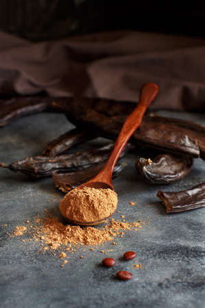 Dry carob pods and powder close up on a gray tableの写真素材