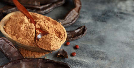 Dry carob pods and powder close up on a gray tableの写真素材