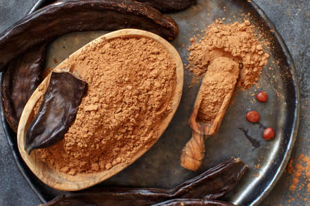 Dry carob powder and pods top view on a gray tableの写真素材