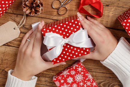 Hands with wrapped present top view on a wooden table