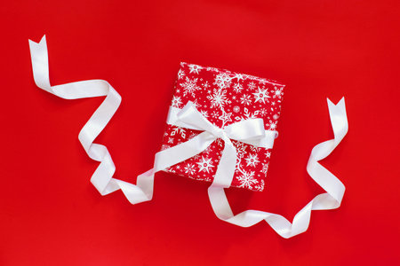 Red gift box with white satin ribbon isolated on red