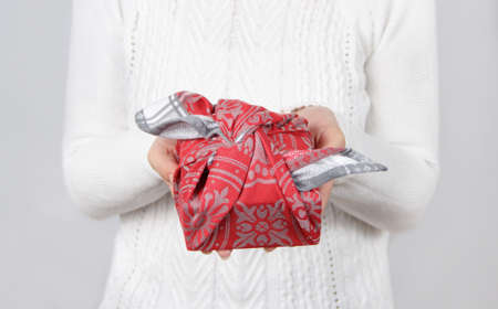Furoshiki eco-friendly gift wrapped in cloth in woman's hands. Zero wasteの写真素材