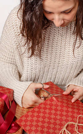 Young woman cutting craft paper and wrapping presents close upの写真素材
