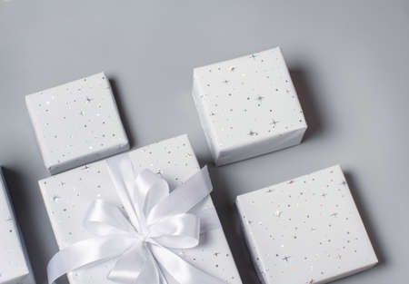 Wrapped gray Gift boxes with white ribbon on gray top viewの写真素材