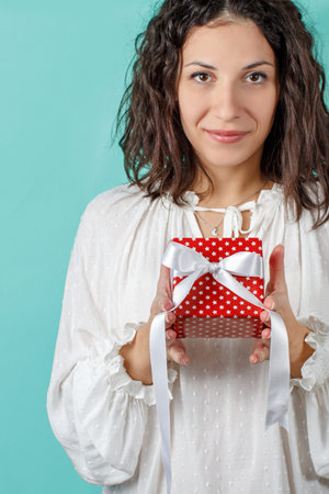 Young woman holding Gift package in hands close up on light green