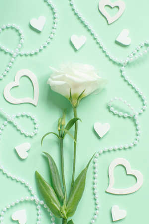 White flower with pearls and hearts around on a light green background  top viewの写真素材