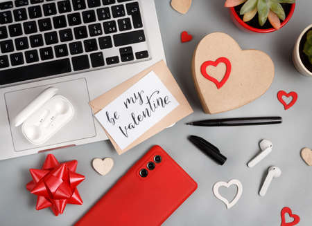 Valentines Day concept with modern gadgets and BE MY VALENTINE card top view on grey tableの写真素材