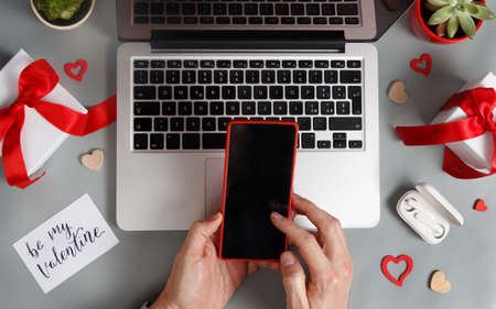 Valentines Day concept with modern gadgets and hands using smartphone top view on grey tableの写真素材