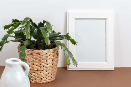 Front view of white poster frame mockup with  plant in a pot over the white wallの写真素材