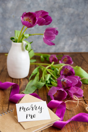 Bouquet of purple tulips and MARRY ME card on wooden table close upの写真素材