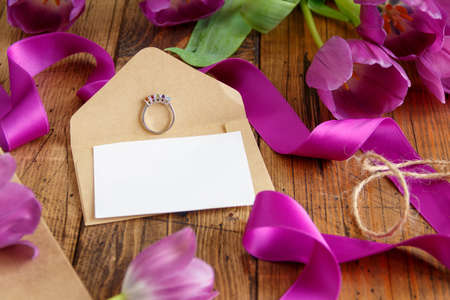 Purple tulips, ring and blank  card on wooden table close upの写真素材