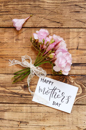 Happy Mother's Day card and pink flowers on a wooden table  top viewの写真素材