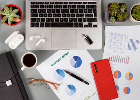 Office desk with reports and modern gadgets near laptop and coffee cup top viewの写真素材