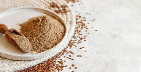 Raw Flax seeds flour in a ceramic plate with a spoon close up